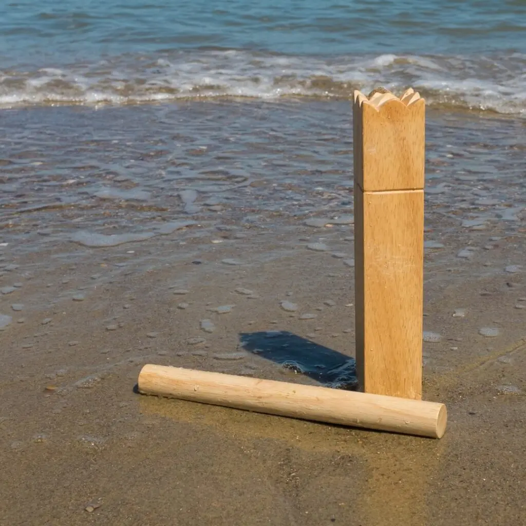 Zwei Holzklötze des skandinavischen Spiels Kubb stehen auf dem Strand im nassen Sand. Im Hintergrund sieht man ruhige Wellen des Meeres. 