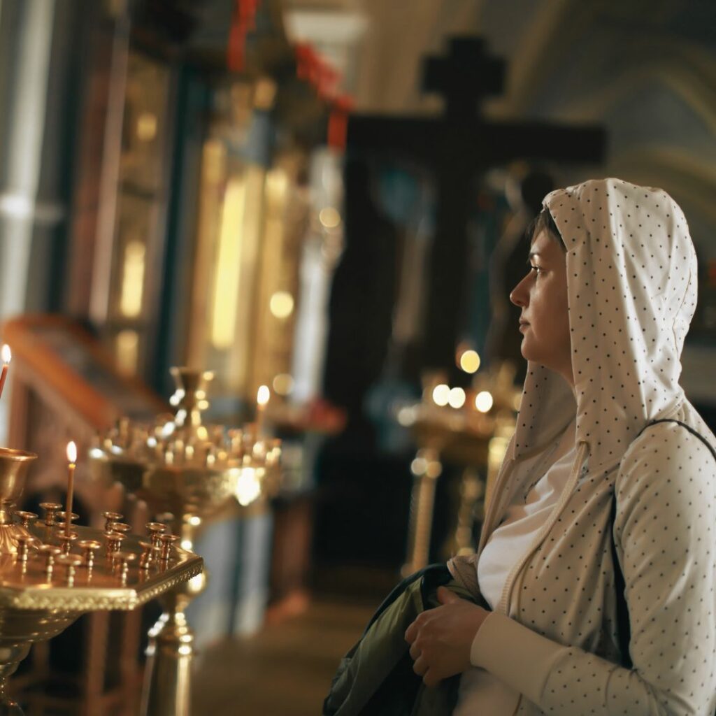 Eine Frau in einer orthodoxen Kirche mit einer Kapuze über dem Kopf.