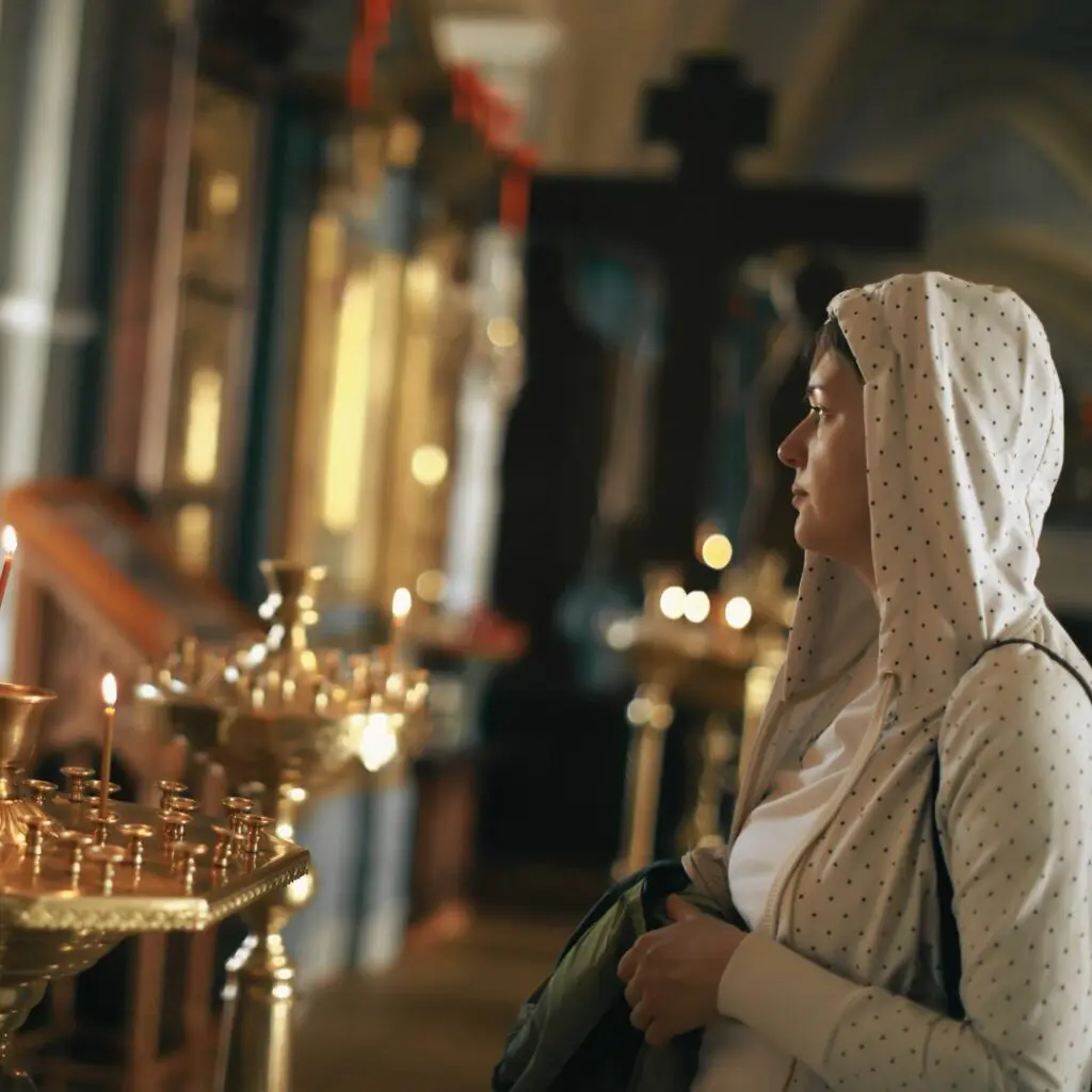 Eine Frau in einer orthodoxen Kirche mit einer Kapuze über dem Kopf.