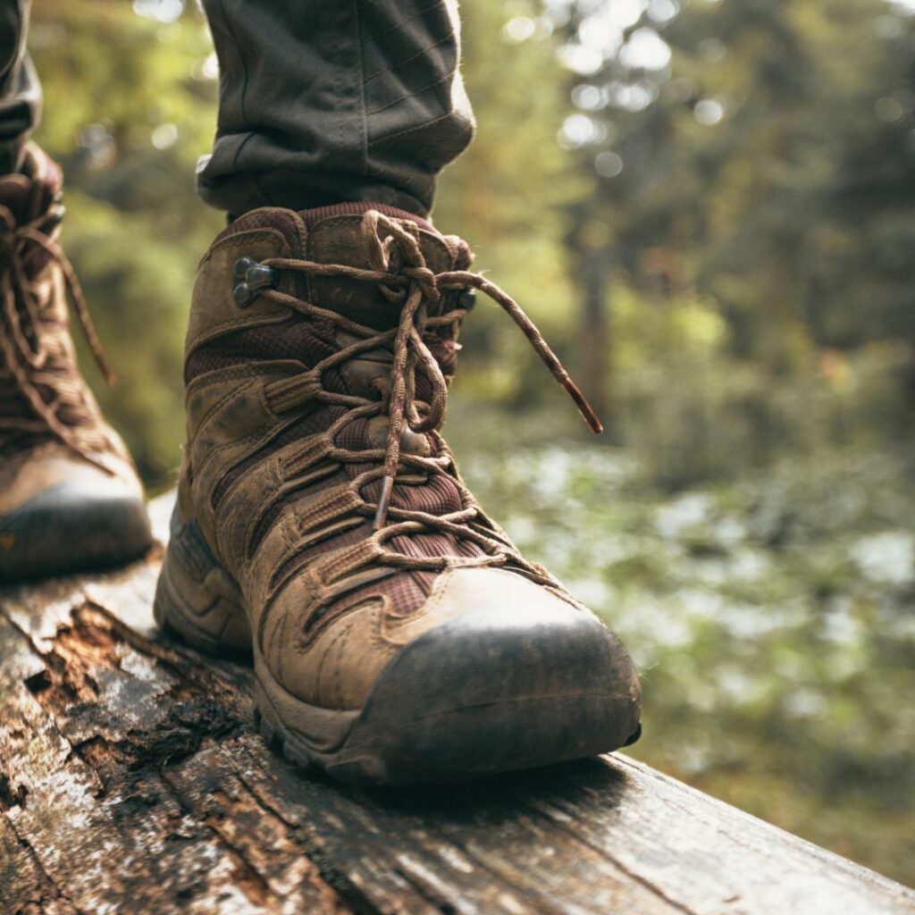 Eine Person läuft mit Wanderschuhe auf einem Baumstamm.