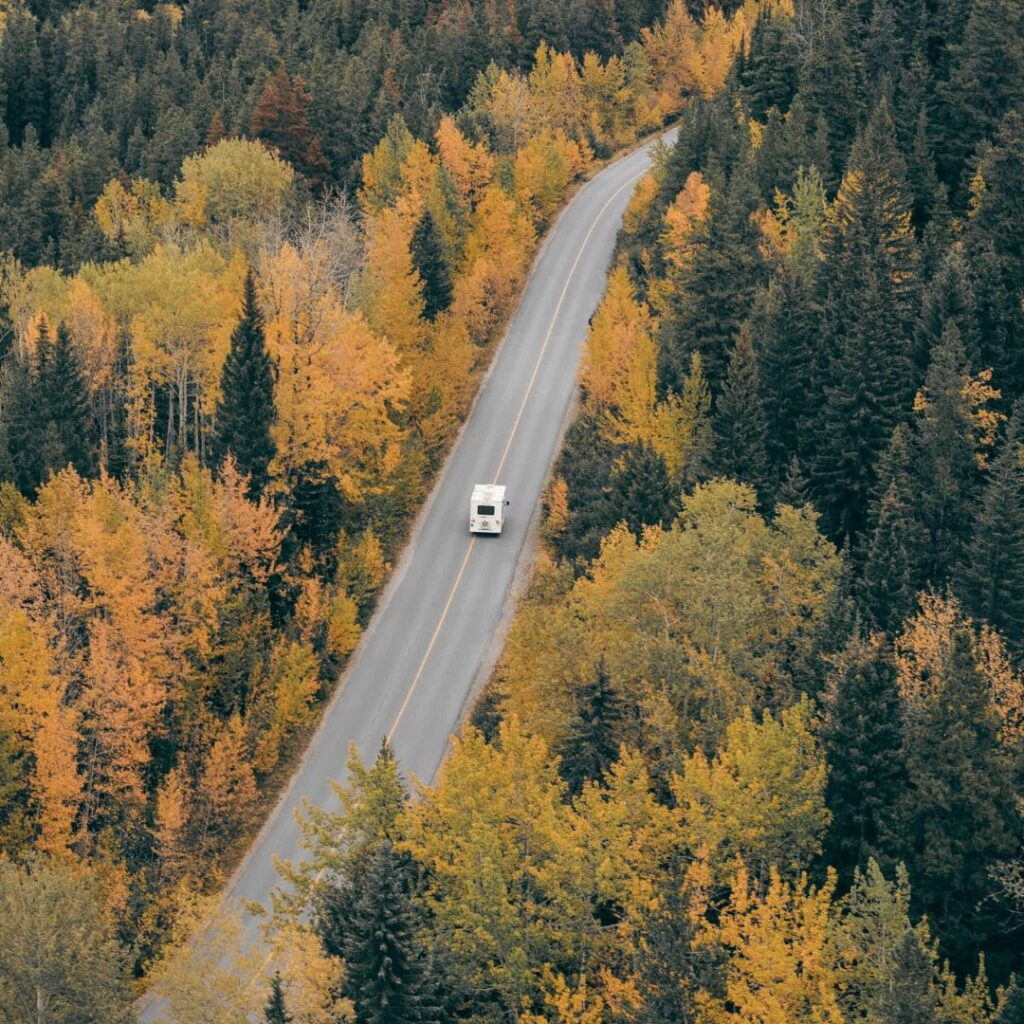 Ein Wohnmobil, dass auf einer Landstraße durch eine Waldlandschaft fährt.