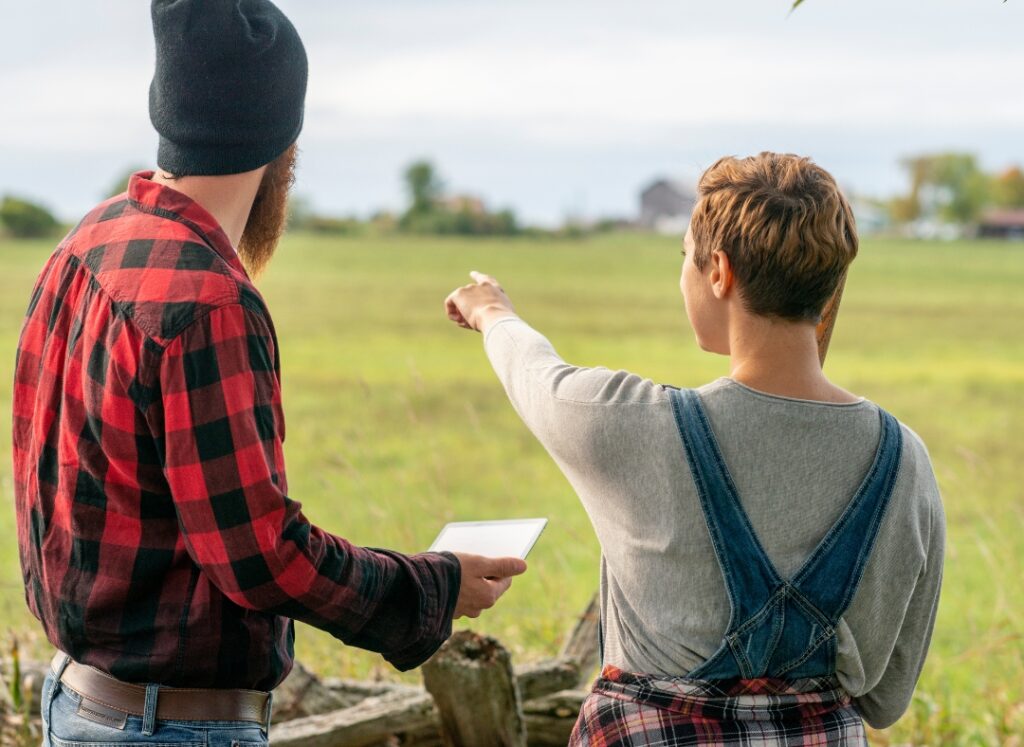 Ein junges Pärchen schaut auf eine Wiese und diskutiert miteinander. 